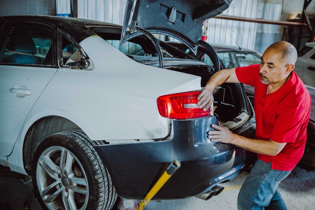 Maestro midiendo con regla de comparación el costado trasero de un Audi para verificar la geometría de la carrocería
